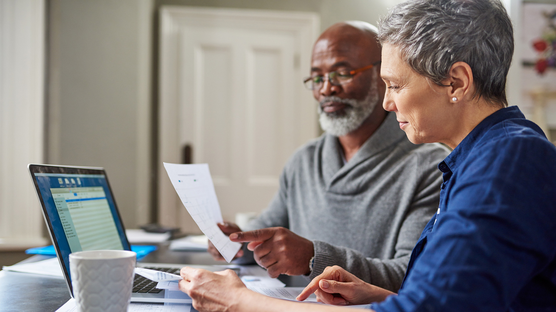 Two people sit at a table and go over documents.